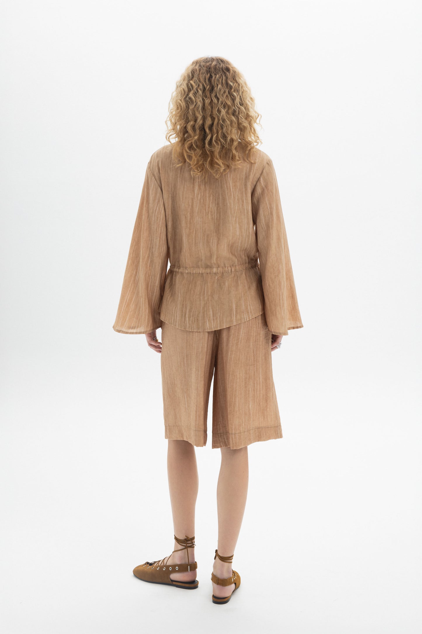 Back view of a woman wearing a Drawstring Waist Blouse with relaxed fit and adjustable waist.