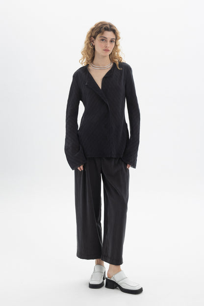 Model wearing a Ruffled V-Neck Blouse with a relaxed fit, styled with wide-leg pants and modern footwear.