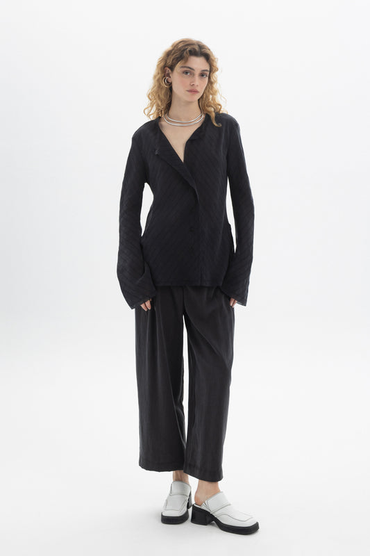 Model wearing a Ruffled V-Neck Blouse with a relaxed fit, styled with wide-leg pants and modern footwear.