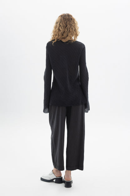 Back view of a model wearing a Ruffled V-Neck Blouse with relaxed-fit pants.