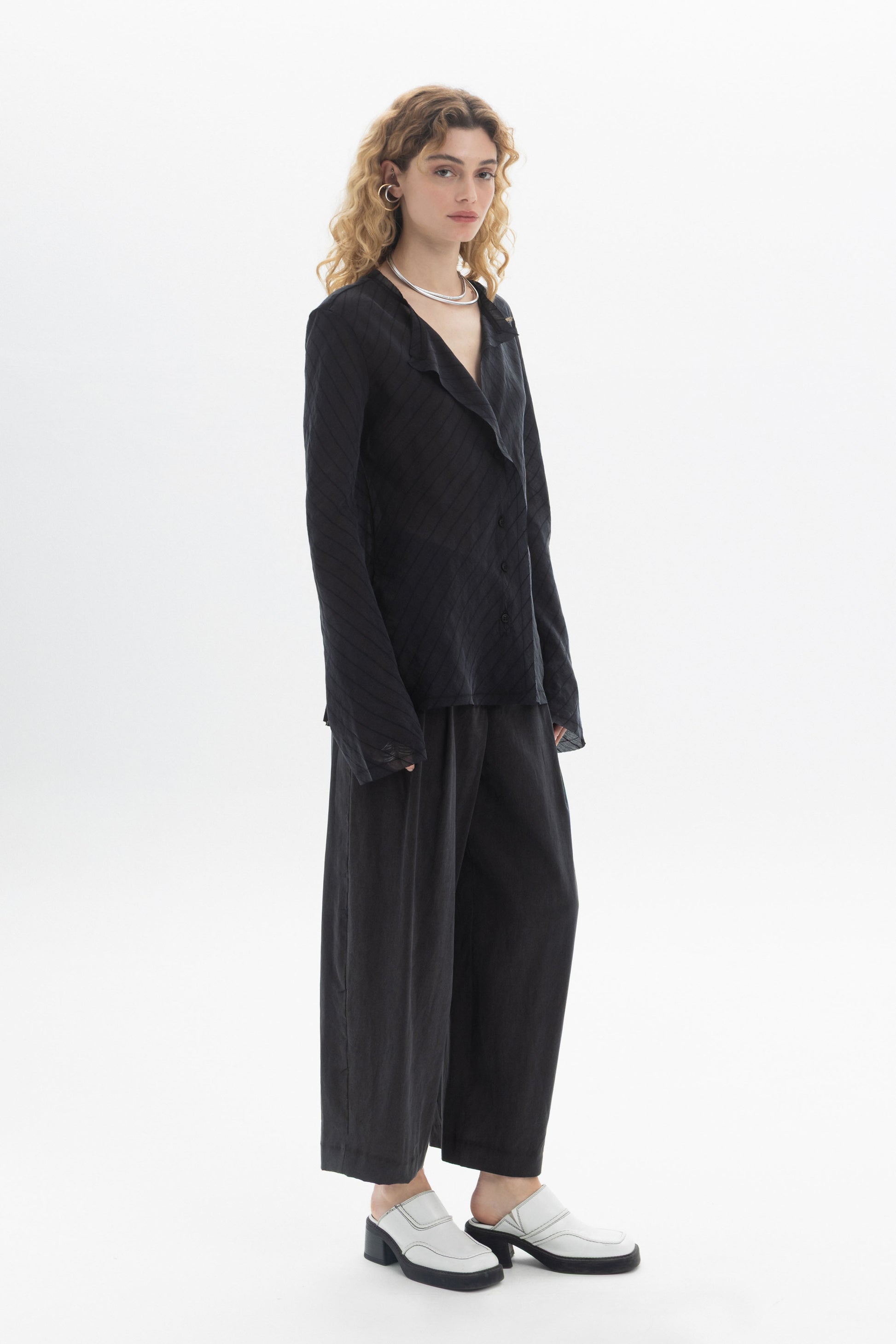 Model wearing a Ruffled V-Neck Blouse styled with wide-leg trousers and modern shoes.