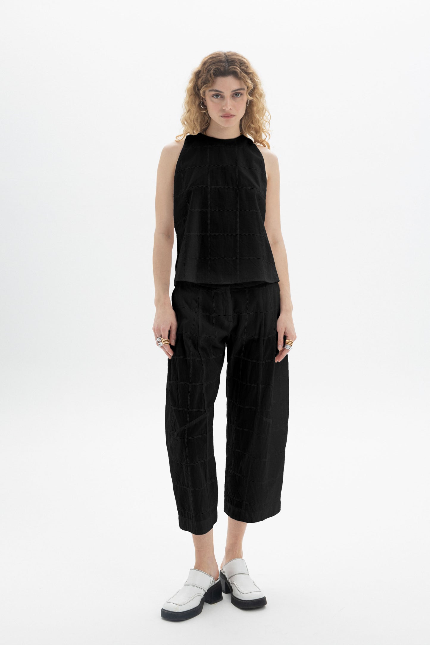 Model wearing a Sleeveless High-Neck Top paired with relaxed fit black pants, showcasing a modern silhouette.