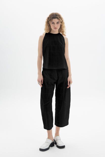 Model wearing a Sleeveless High-Neck Top paired with relaxed fit black pants, showcasing a modern silhouette.