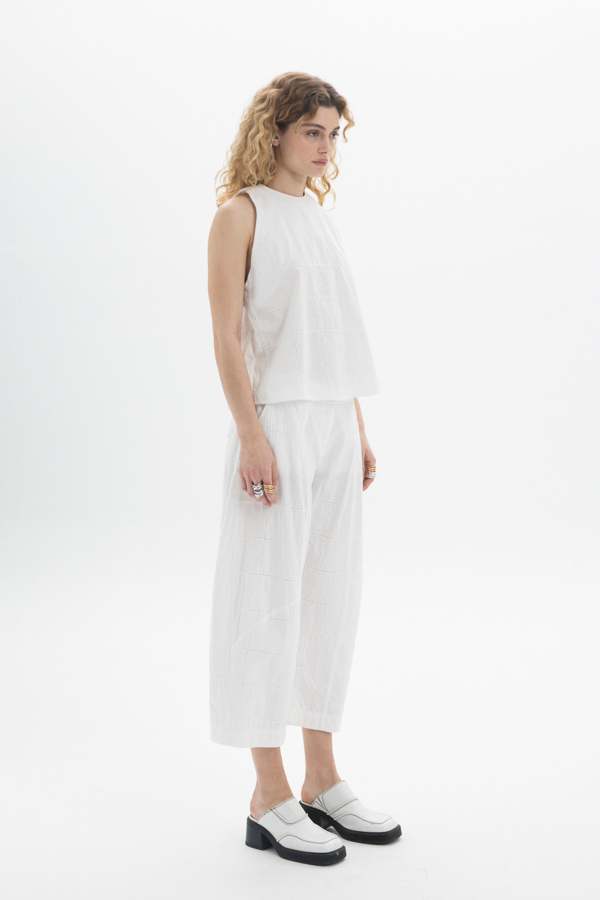 Model wearing a Sleeveless High-Neck Top in white, showcasing a modern and relaxed fit with subtle texture.