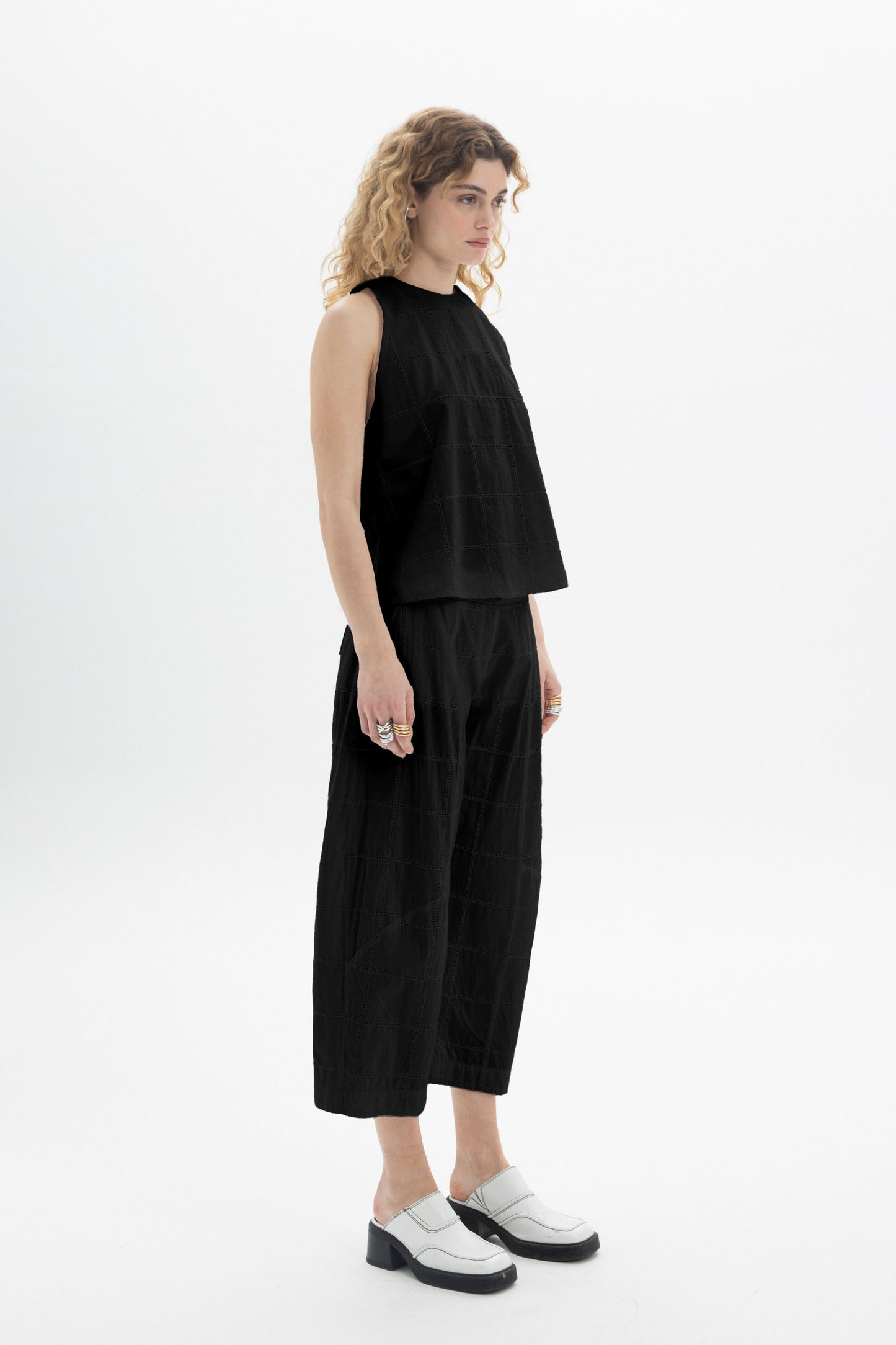 Model wearing a sleeveless high-neck top paired with relaxed-fit black bottoms, showcasing a modern style.
