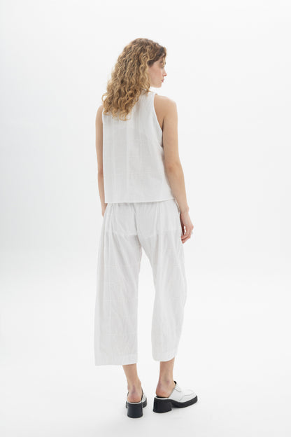 Model wearing a sleeveless high-neck top in white, showcasing a modern relaxed fit from the back.