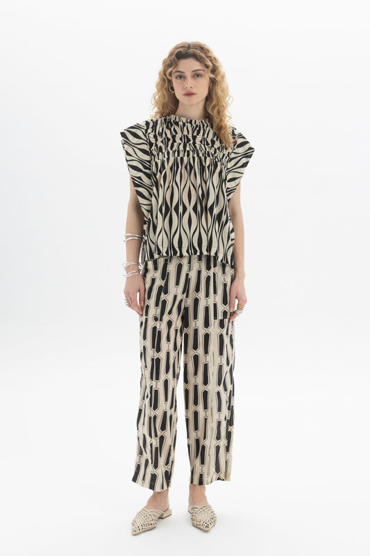 Gathered Sleeveless Top worn with patterned pants, showcasing relaxed fit and contemporary style in a stylish outfit.