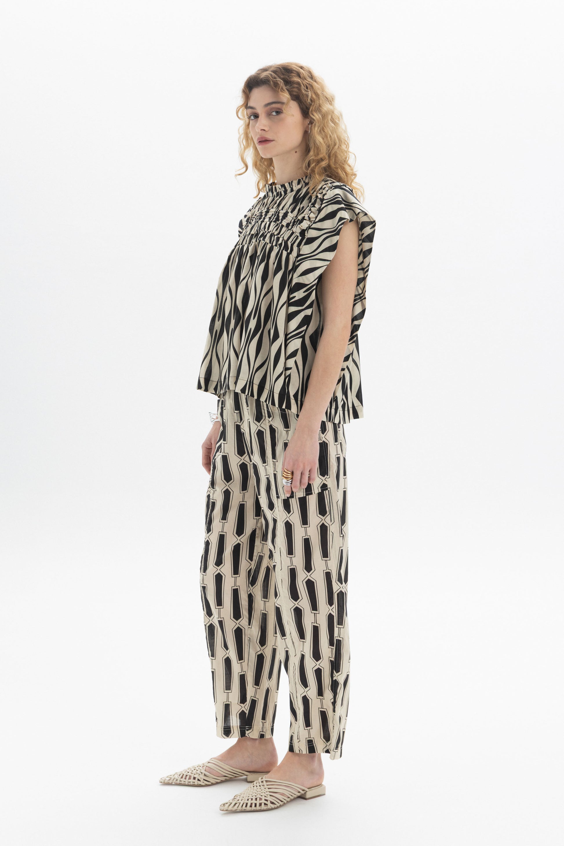 Gathered Sleeveless Top featuring gathered detailing and relaxed fit, styled with patterned pants.