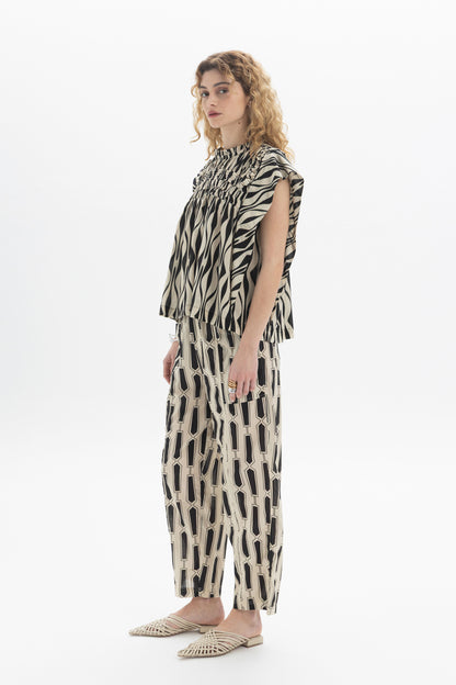 Gathered Sleeveless Top featuring gathered detailing and relaxed fit, styled with patterned pants.