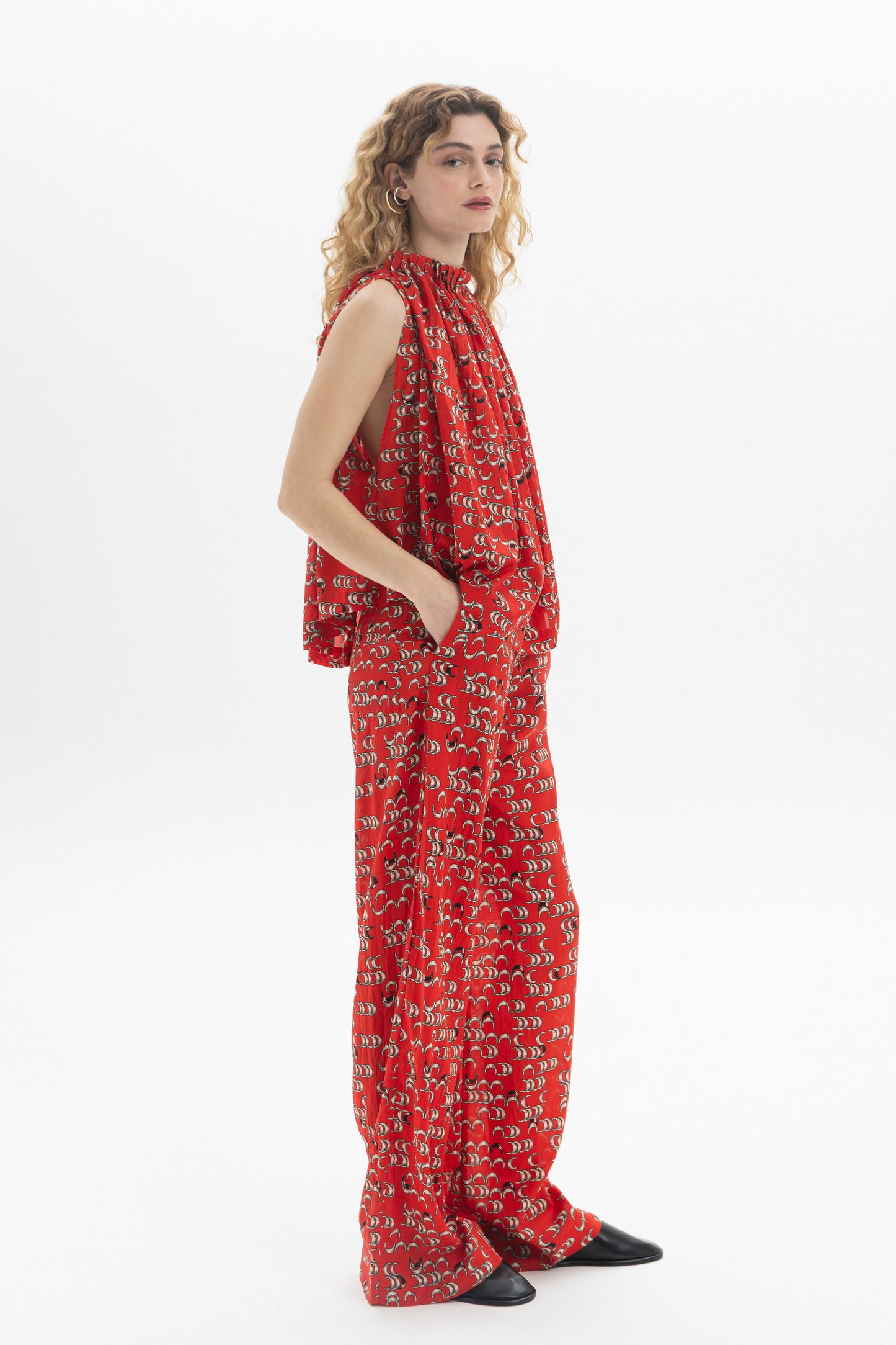 Model wearing a Draped High-Neck Top in a vibrant red pattern, showcasing its fluid drape and soft volume.