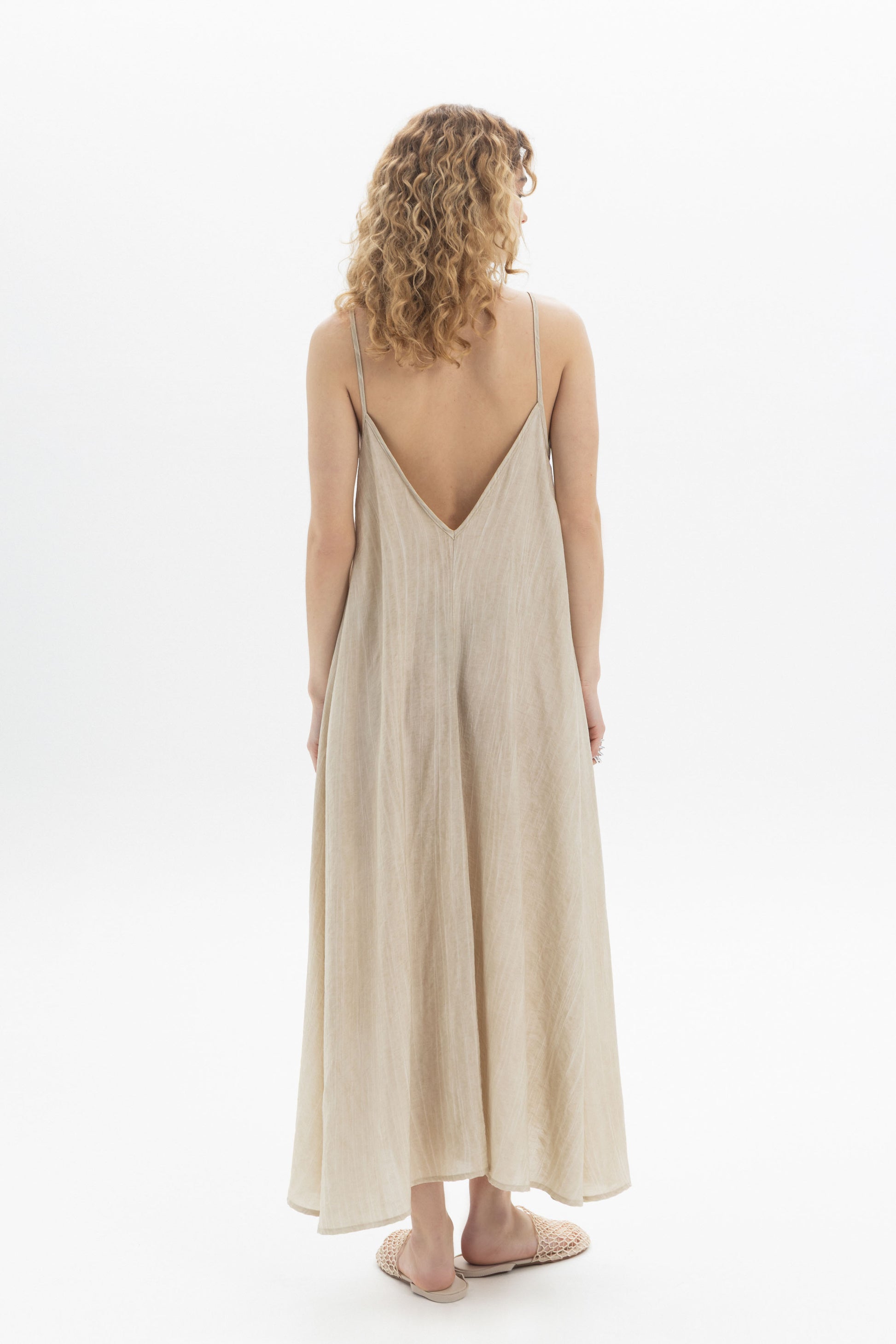 Back view of a model wearing a Long Slip Dress with thin straps and V-neckline in a soft fabric.