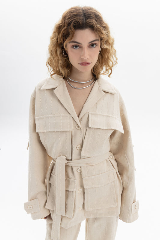 Belted Denim Utility Jacket in a light cream color featuring structured collar and multiple flap pockets.