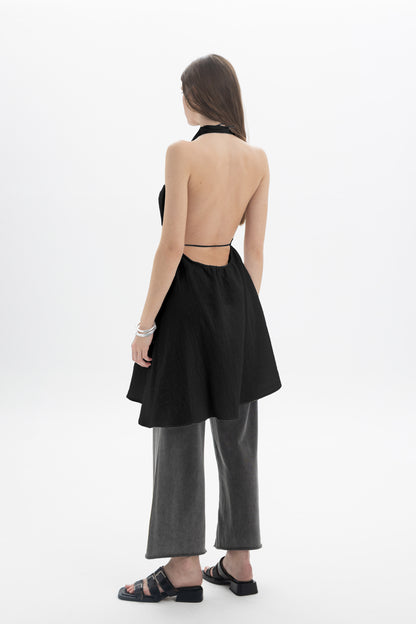 Model wearing a Longline Halter Top with a deep open neckline and draped panels, paired with wide-leg pants.