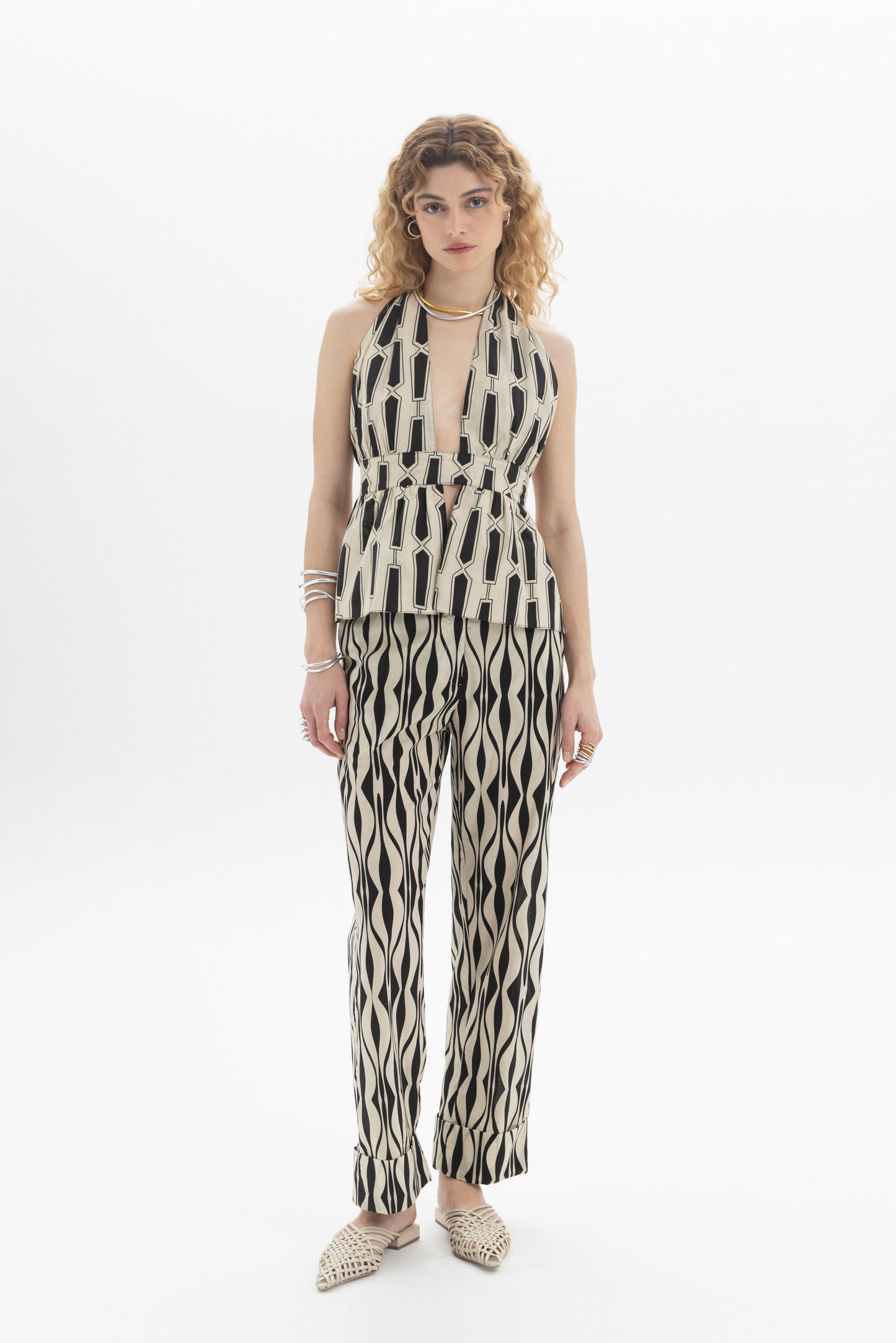 Model wearing a Halter Peplum Top with geometric print, paired with matching pants, featuring a fitted waistband and tie back.