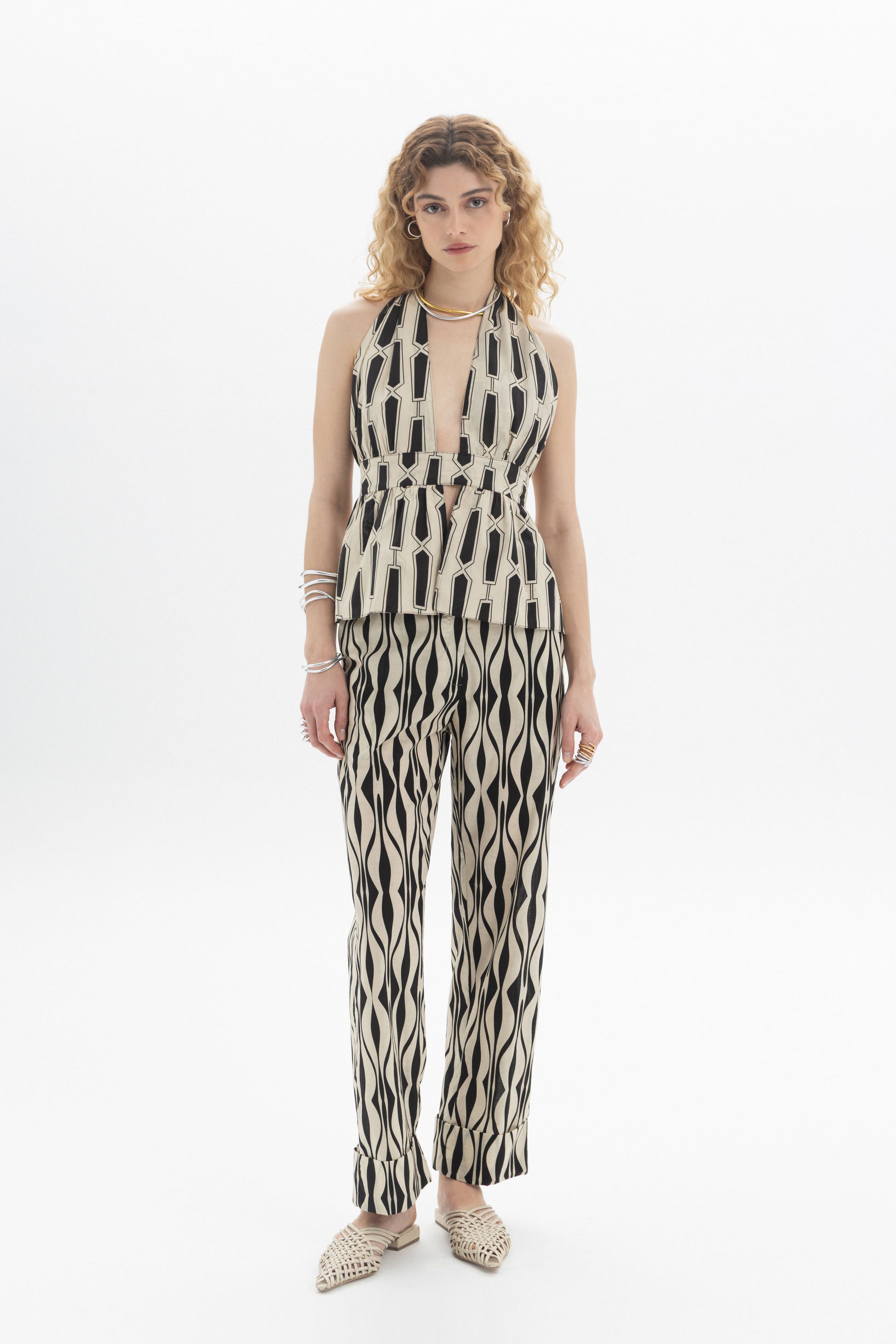 Model wearing a Halter Peplum Top with geometric print, paired with matching pants, featuring a fitted waistband and tie back.
