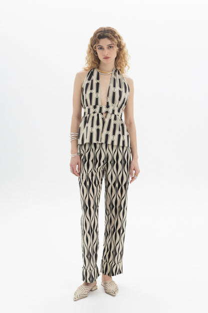 Model wearing a Halter Peplum Top with geometric print, paired with matching pants, featuring a fitted waistband and tie back.