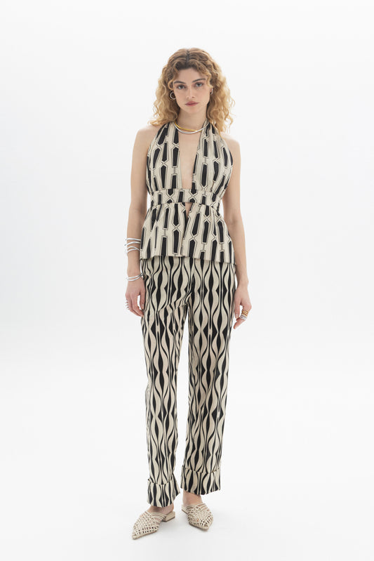 Model wearing a Halter Peplum Top with geometric print, paired with matching pants, featuring a fitted waistband and tie back.