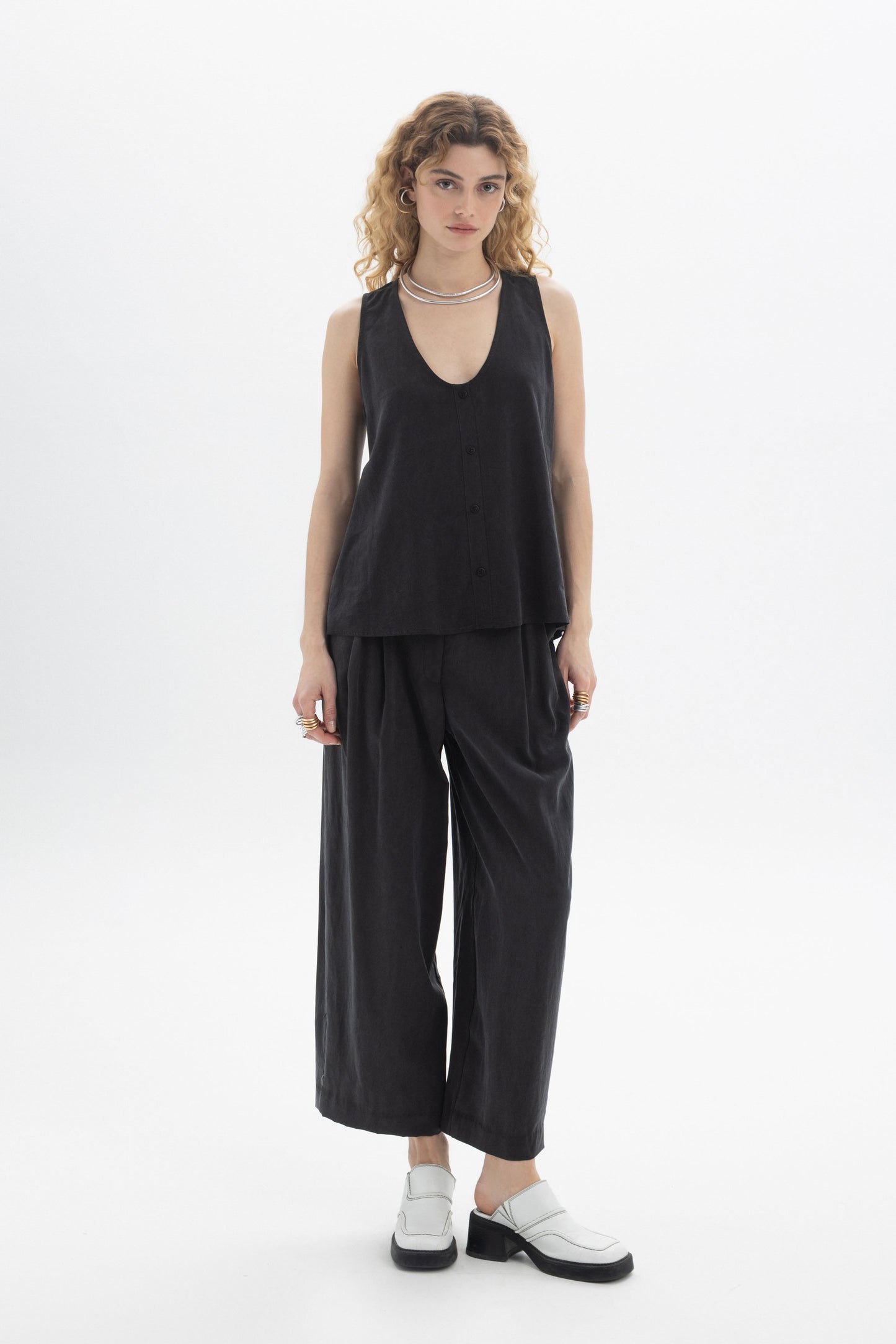 Model wearing a black Sleeveless Button Top with a deep V-neckline and front button closure in Tencel.