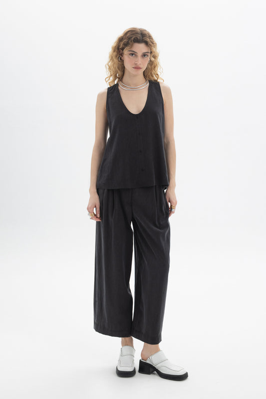 Model wearing a black Sleeveless Button Top with a deep V-neckline and front button closure in Tencel.