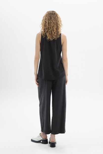 Back view of a model wearing a black Sleeveless Button Top paired with relaxed trousers.